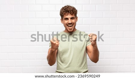 young man shouting triumphantly, laughing and feeling happy and excited while celebrating success