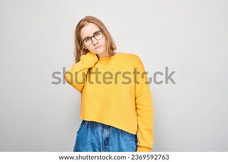 Portrait of young student girl suffering from pain, touching neck isolated on white studio background. Psychosomatics of stress, degenerative disease of spine

