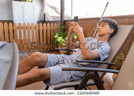Teenager lying on a terrace using a mobile phone qith bored face