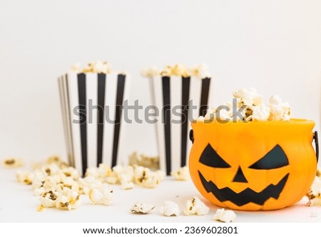 Jack o lantern basket and cinema stripped boxes with popcorn on a white background. Halloween entertainment concept. Cinema or TV watch at halloween night.