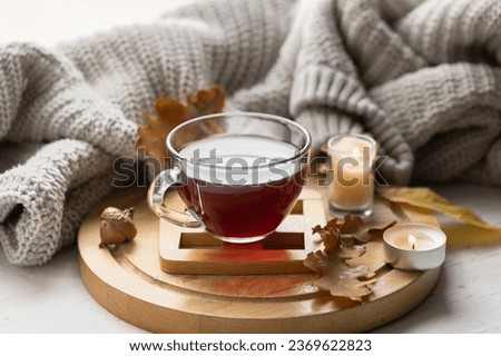 Autumn composition with a cup of tea, leaves and a knitted element.
