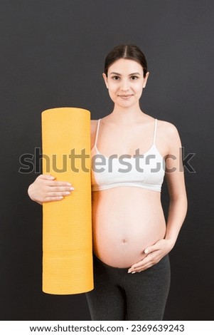 Pregnant Girl Holding Yoga Mat Standing Over Colored Background. Studio Shot, Free Space For Design.