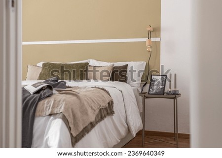Side shot of edge of large cozy double bed with a bedside table in beige color in a hotel room. The concept of comfortable living in a business hotel with a convenient location and five-star service