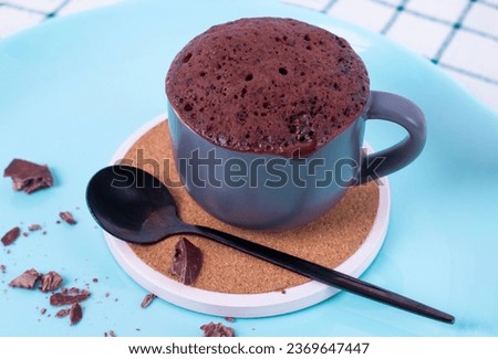 mugcake is microwaved. Homemade cupcake in a mug is on a plate. Chocolate brownie mug cake. Easy cooking concept, microwave baking. muffin chocolate. High quality photo Royalty-Free Stock Photo #2369647447