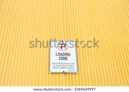 no parking loading zone unauthorized vehicles will be tagged and or towed at owners expense sign on yellow wall