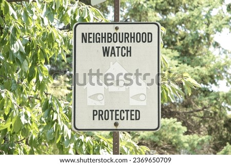 neighbourhood watch protected writing caption text rectangle sign on post with tree behind and faced picture illustrations of homes houses with eyes on in them, black and white