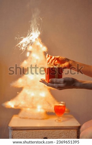 sparkler in woman's hand, gift birthday or Christmas party. shining spark lights. celebrating new year with your family. screen saver, background. Garland in form of Christmas tree, home decoration