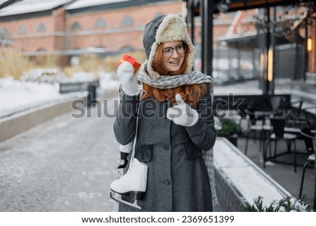 European millennial woman holds in hands red gift for birthday, Christmas, Valentine's day. happy woman in winter clothes walks in park on date and enjoys life. Winter holidays love freedom