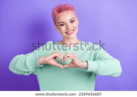 Portrait of gorgeous cheerful girl arms fingers demonstrate heart symbol green sweater isolated on purple color background