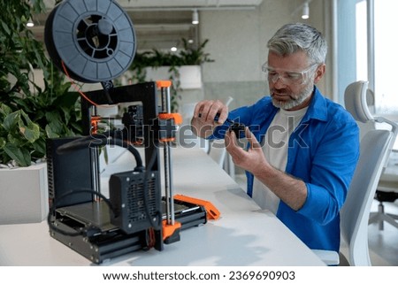 Modern 3D printer equipment and man working with it in office.
