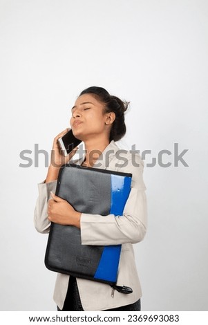 Cheerful corporate office lady holding a folder and a smartphone. Young woman in formal wear wearing white blazer against white background.