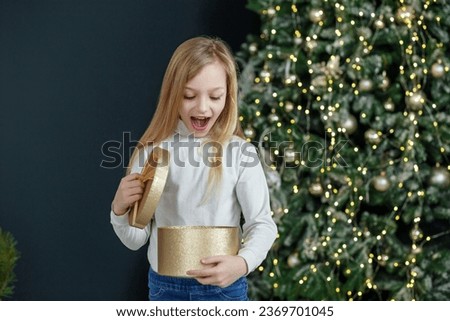 Child opening gift box. Concept New Year, Merry Christmas, holiday, vacation, winter, childhood. Cozy home. Copy space.