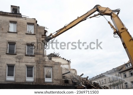 Dismantling by builders of the wall of an old building with several floors using an excavator with a manipulator crane. View from below