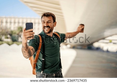 A smiling visitor is taking self portraits on the street during his vacation in Europe.