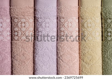 Stack of Rolled Towels with ornament for hotels and saunas in various pastel colors. Close up