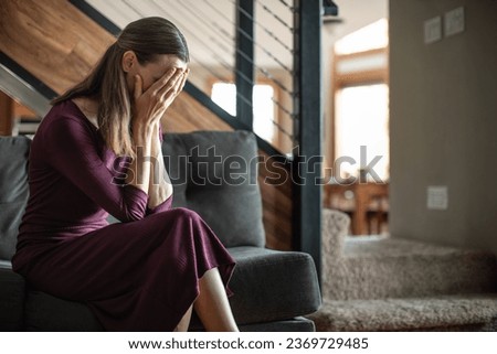 Sad and depressed woman sitting alone at home  Royalty-Free Stock Photo #2369729485