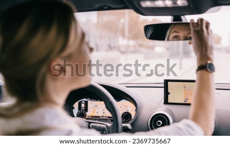 Woman driver adjusting the rear view mirror Royalty-Free Stock Photo #2369735667