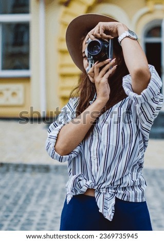 caucasian woman in trendy hat and apparel having journey in town making photos enjoy hobby