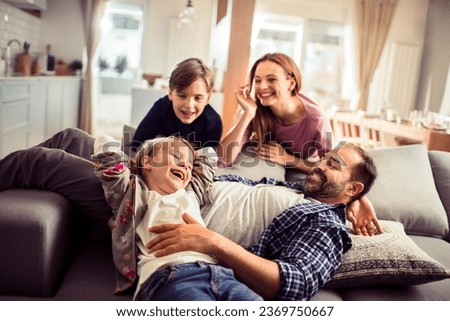Happy young caucasian family being playful and having fun together on the couch in the living room at home Royalty-Free Stock Photo #2369750667