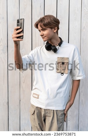 teen boy taking selfie on a white wooden background outdoor, sharing in social media, teen lifestyle, blogging, teenager self-admiration, self obsession