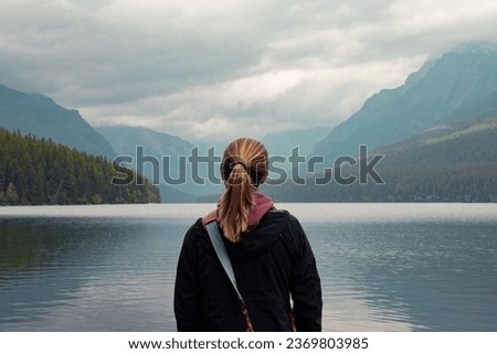 Woman standing looking at blue lake and mountains Royalty-Free Stock Photo #2369803985
