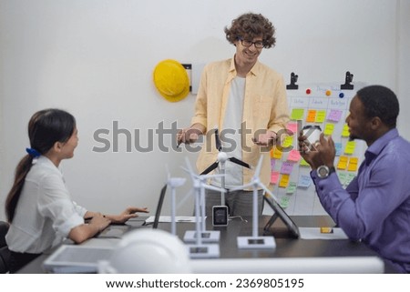 A diverse startup team develop, collaborates on a powerful, lightweight, portable wind turbine prototype, aligning with potential user demand and renewable energy needs to secure investor funding. Royalty-Free Stock Photo #2369805195