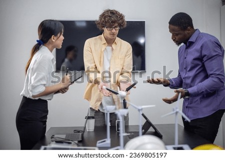 A diverse startup team develop, collaborates on a powerful, lightweight, portable wind turbine prototype, aligning with potential user demand and renewable energy needs to secure investor funding. Royalty-Free Stock Photo #2369805197