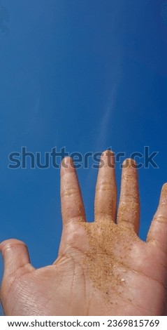 sand in hand on blue sky background