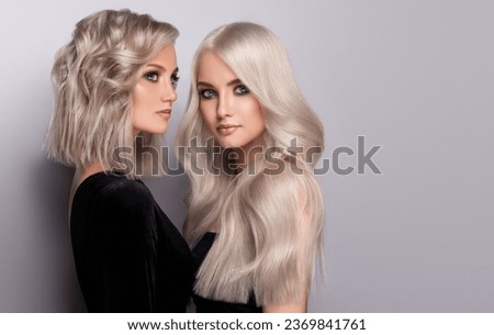 Two beautiful woman with hair coloring in blond. Girl Stylish hairstyle curls done in a beauty salon.  Cosmetics and makeup Royalty-Free Stock Photo #2369841761