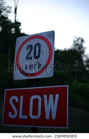 Slow sign with 20kmh with greenery in the background