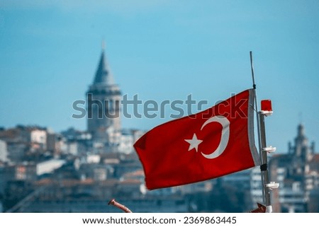 Galata Tower and Turkish flag waving on the boat in the background.