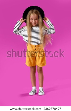 Cute little girl in hat on purple background