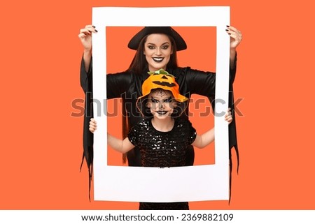 Little girl and her mother dressed for Halloween with frame on orange background