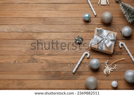 Christmas balls with gift box and candy canes on wooden background