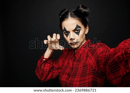 Young woman with Halloween makeup face art mask wears clown costume red dress do creepy selfie shot pov mobile cell phone isolated on plain solid black background studio. Scary holiday party concept