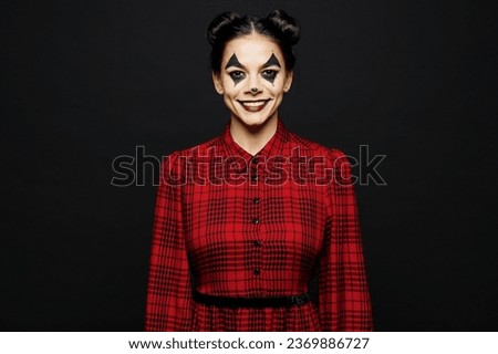 Young smiling cool woman with Halloween makeup face art mask wearing clown costume red dress looking camera isolated on plain solid black wall background studio portrait. Scary holiday party concept