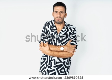 young handsome man wearing printed shirt shaking and freezing for winter cold with sad and shock expression on face.