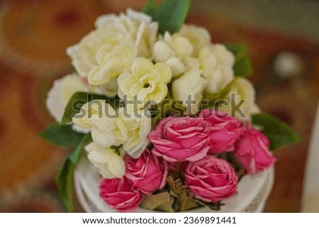 A bouquet of white roses in a cup on a wooden table