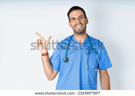 young doctor man wearing medical uniform pointing up with fingers number eight in Chinese sign language BÄ.