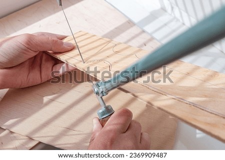 Schoolboy with fret saw or jigsaw for sawing on plywood. Сarving, handicraft and carpentry lesson at school.  Royalty-Free Stock Photo #2369909487