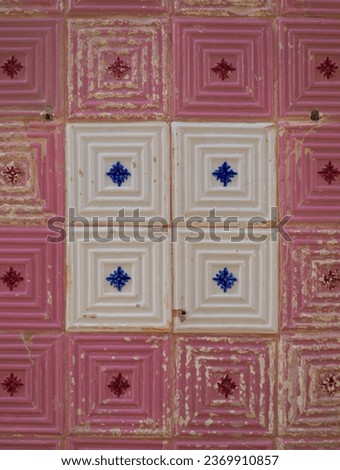 Part of a typical Portuguese wall decorated with tiles. Nice pink, blue and white colors. Worn tiles. Portugal. Vertical photo.