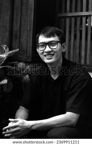 Dong Nai, Vietnam - September 24 2023: Monochrome Portrait: Asian Bookworm in Black Attire, Seated in a Japanese style Café Corner with Cultural Decor