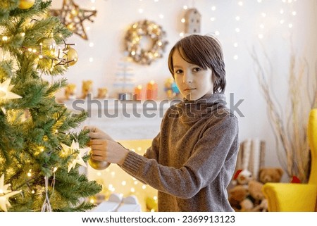 Cute child, boy, playing in decorated room for Christmas, decorating Christmas tree