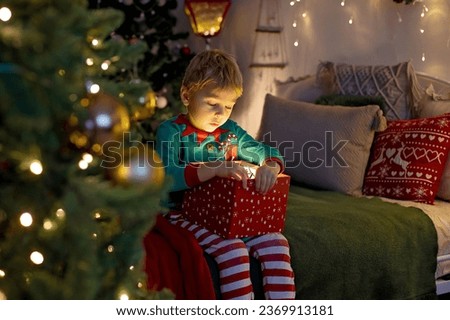 Cute preschool child, blond boy with pet dog, opening presents at home, decorated Christmas room  at home