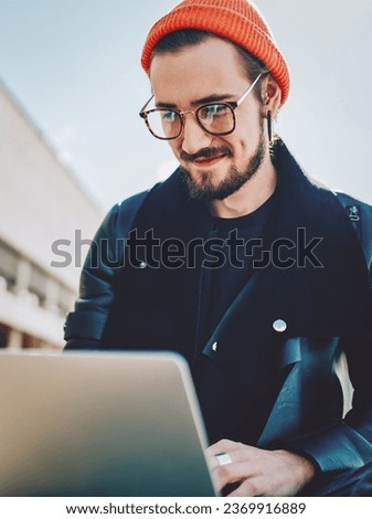  positive hipster guy in stylish wear reading news on website