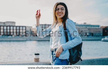 Positive hipster girl with backpack taking picture