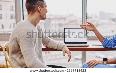 Positive young man and woman dressed in casual wear laughing during friendly conversation
