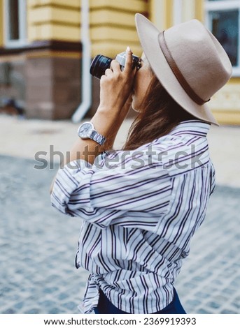 Caucasian female tourist taking pictures of urban settings during strolling in city using retro camera