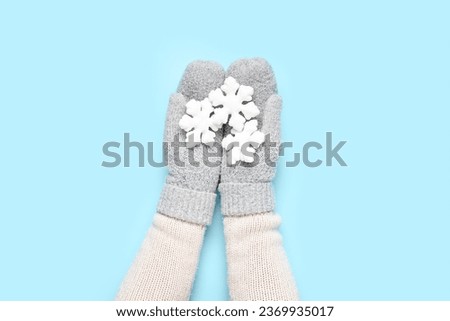 Female hands in warm mittens with beautiful Christmas decorations on color background, closeup