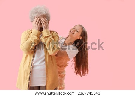 Little girl and her grandmother closing eyes on pink background Royalty-Free Stock Photo #2369945843